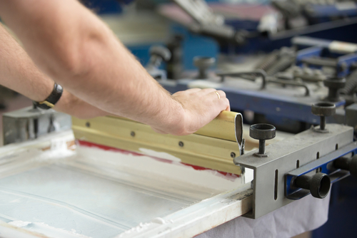 creating an image on white fabric clothing by pressing ink through a screen