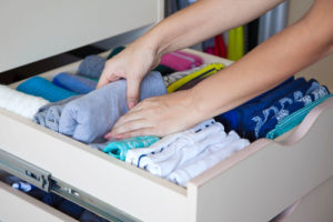 woman folding t shirts in drawer