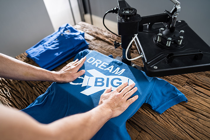 Man Printing On T Shirt In Workshop